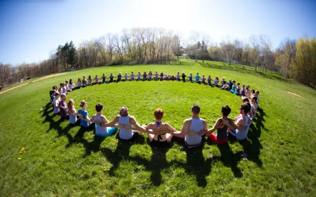 AcroYoga community sitting in a circle on the grass